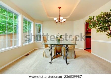Luxury dining room with french window, ivory walls with white moldings and elegant dining table set.
