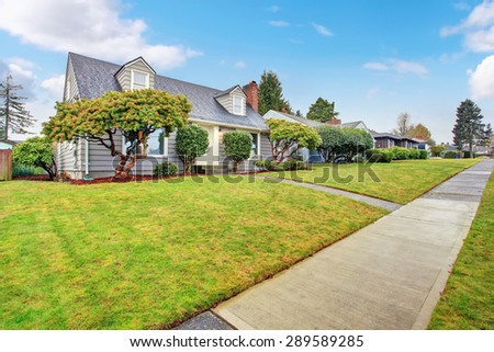Authentic gray house with large lawn and trees.