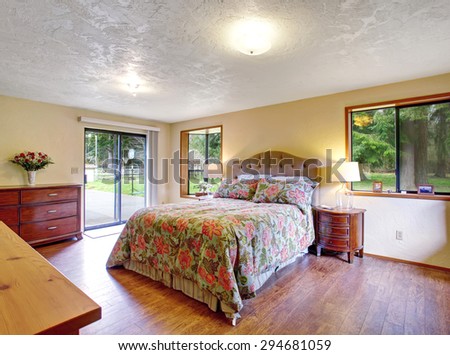 Gorgeous master bedroom with glass door, and dark tone hardwood floor.
