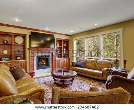 Decorative living room with leather sofas, hardwood floor, and a rug.