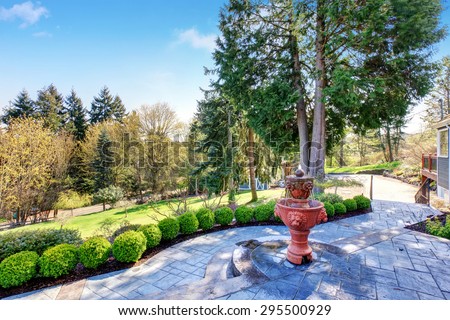 Gorgeous back yard with patio including elegant fountain and lots of greenery.
