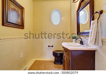 Classy half bathroom with small oval window, and beige tile floor.