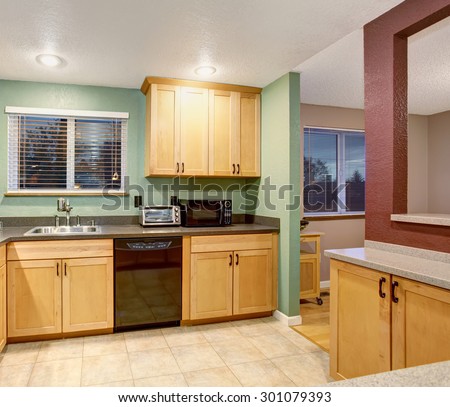 American small house or apartment type typical kitchen for 2014. Tile floor, birch tree light wood cabinets, black color applicances