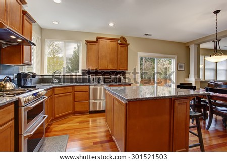 Classic kitchen with island, stainless steel fridge, and many cabinets.