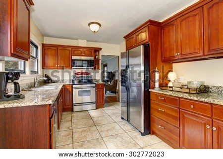 Well defined kitchen with large tile floor, and stained cabinets.