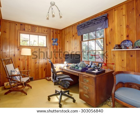 Traditional home office with wood panel walls, and a nice desk.