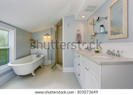 All white luxury master bathroom with vintage bathtub and tile floor.