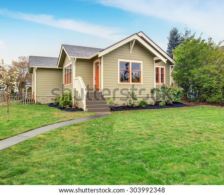 beige home with orange and white trim, also grass filled lawn.