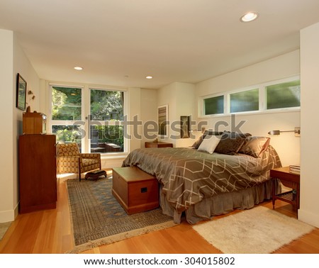 Luxury master bedroom with large brown bed, and four piece window.