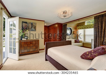 Luxury master bedroom with whites and browns as decor tones, along with a balcony.
