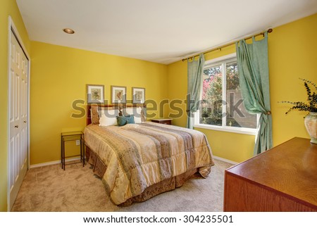 Bright bedroom with yellow interior paint and beautiful decorative bedding.