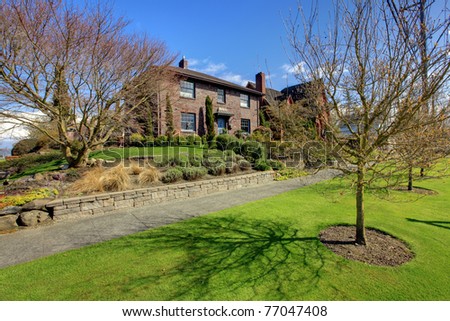 Brick English style old historical house with blue doors adn trims and bright sunny spring landscape.
