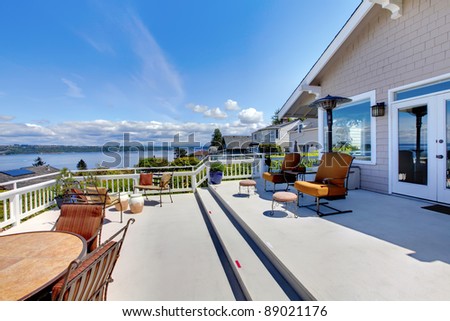 Large white house terrace with water view during summer.