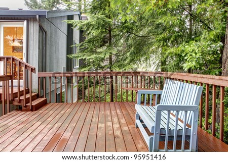 Small deck with blue chair and grey house.