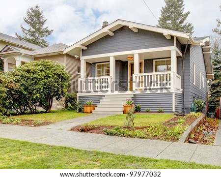 Rain-streaked bue grey small craftsman style house with white porch.