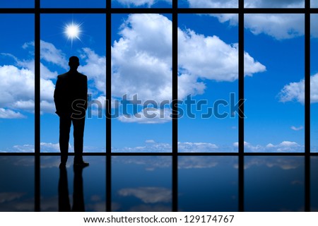 Business Man looking out of high rise office window at blue sky bright sunshine and white clouds.