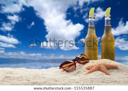 Two cold beers with lime in a beautiful tropical beach setting with sunglasses and starfish