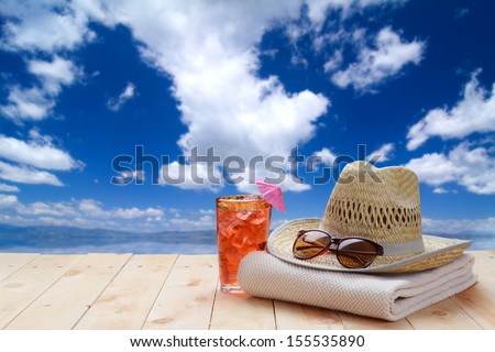 Sunglasses on a wood platform (boat dock or board walk) on a bright sunny day with blue sky and water background.