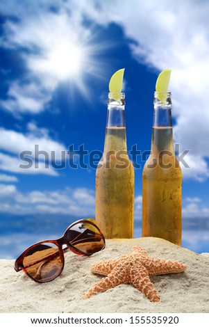 Two cold beers with lime in a beautiful tropical beach setting with sunglasses and starfish