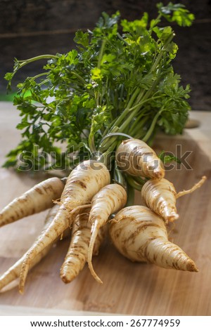 Parsley root with leaves on bamboo cutting board