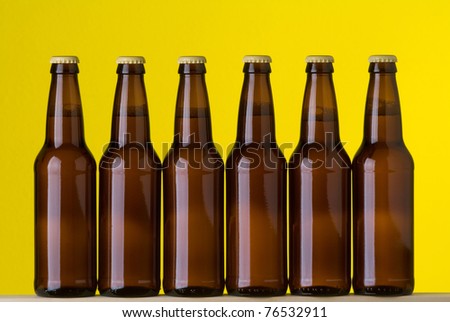 Six bottles of beer side by side on a yellow background