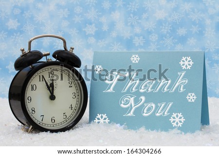 An old-fashion alarm clock with a Thank You blue card on snow and a blue snowflake background, Christmas is a Time to be Thankful