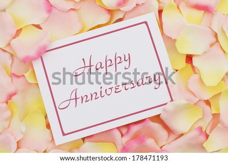 Happy Anniversary card, A white card with text Happy Anniversary and a pink and yellow rose pedal backgrounds