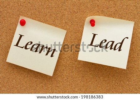 Learn and Lead, Two yellow sticky notes on a cork board with the words Learn and Lead