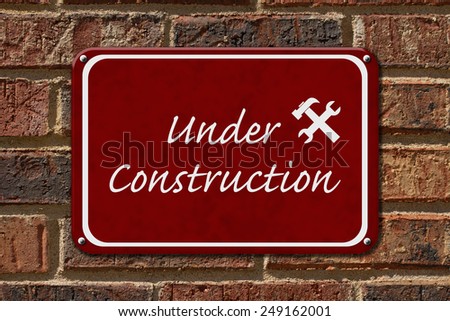 Under Construction Sign,  A red sign with the words Under Construction with hammer and wrench on a brick wall