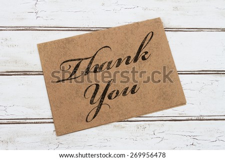A thank you card, A brown card with words Thank You over a distressed wood background