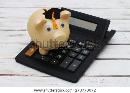 Calculating your education costs, A golden piggy bank with a grad hat on a calculator over a distressed wood background