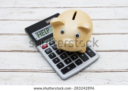 Help with your savings, A golden piggy bank on a calculator with word Help over a distressed wood background