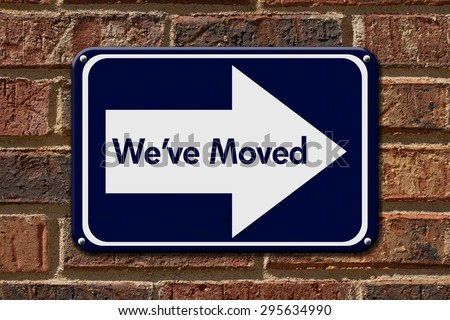 We have Moved Sign,  A blue sign with the word We\'ve Moved with an arrow on a brick wall