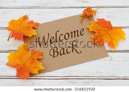 Welcome Back Card, A brown card with words Welcome Back over a distressed wood background with Autumn Leaves