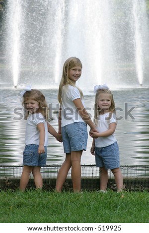 three sisters holding hands in front of a fountain