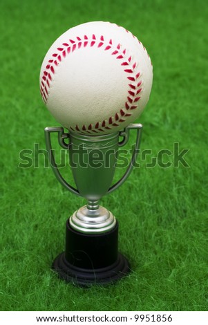 Baseball sitting on top of a trophy on grass