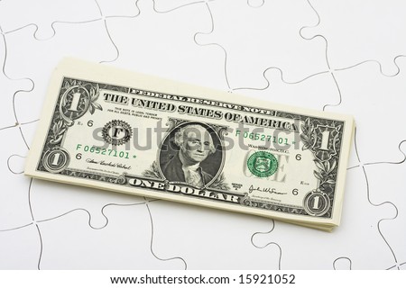 Puzzle with a stack of dollar bills sitting on it. understanding finances