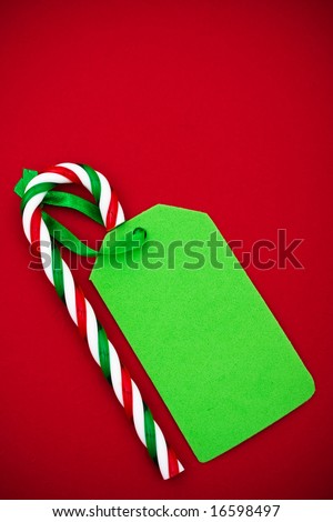 Candy cane with blank green gift tag on red background. sweet gift
