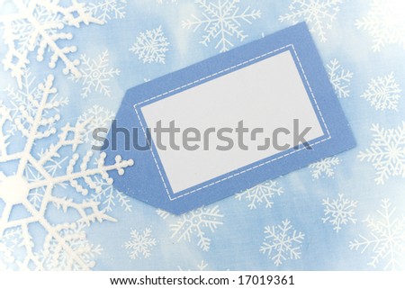 Blue background with close up of snowflake making a border with blank gift tag, snowflake border