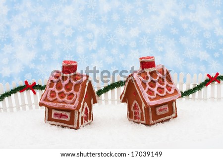 Two gingerbread houses and white picket fence with green garland and red bow, merry Christmas
