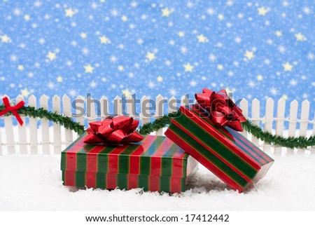 Christmas presents and white picket fence with green garland and red bow, merry Christmas