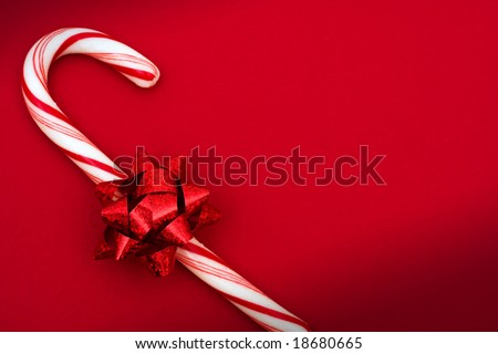 Candy cane with red bow on red background, candy cane