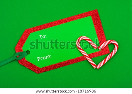 Candy cane with blank green gift tag on green background ? sweet gift