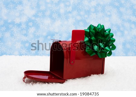 Red mailbox with green bow and the flag up sitting on snow with a snowflake background, mailbox
