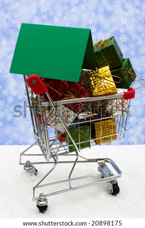 Shopping cart filled with presents on snow and blank gift tag with snowflake background, Christmas shopping