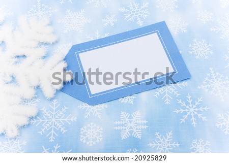 Blue snowflake background with close up of snowflake and a blank gift tag, snowflake background