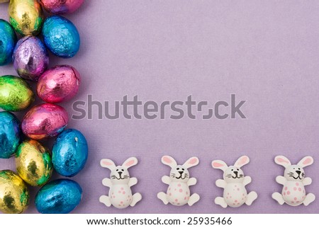 Foil covered Easter eggs and rabbits making a border on a purple background, Easter border