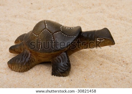 A brown turtle sitting on a sand background, turtle