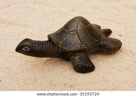 A brown turtle sitting on a sand background, turtle