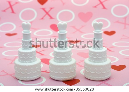 Three white cakes with hearts on top sitting on a love background, love cakes